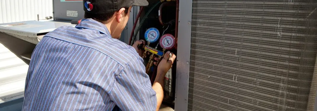 HVAC technician servicing a condenser unit in Clay